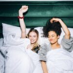 two young women lying on white bed